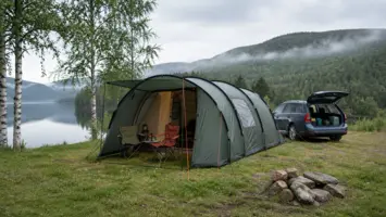 Stort grønt campingtelt med åpent fortelt ved bil og innsjø